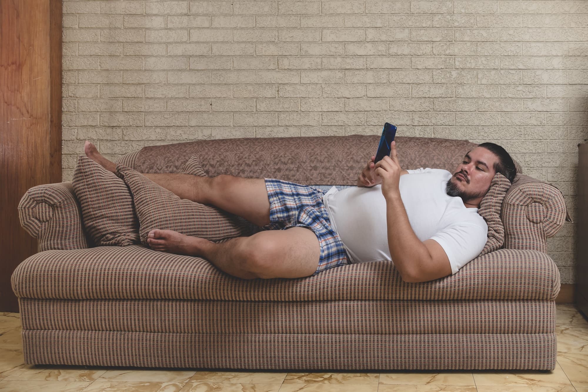 Man lying on couch holding phone